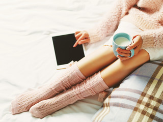 Woman using tablet at cozy home atmosphere on the bed. Young wom