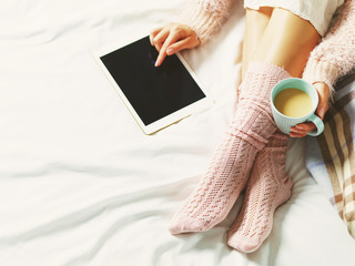Woman using tablet at cozy home atmosphere on the bed. Young bea