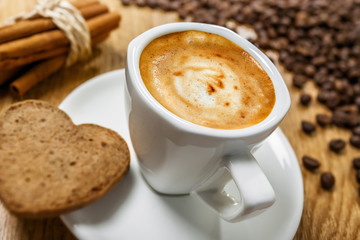 Cup of coffee with cookie heart and cinnamon