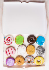 assortment of various colorful donuts in a white paper box , top view