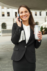 Business woman talking by smartphone, with caffe cup and newspap