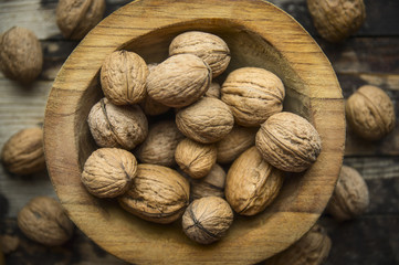 walnuts in a wooden bowl on a rustic wooden background, top view, close up