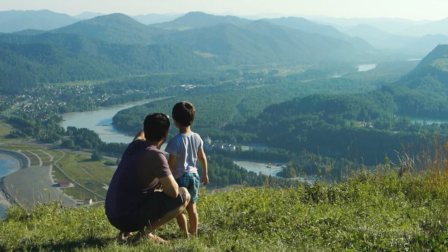 Father with his son are looking to the mountains and river
