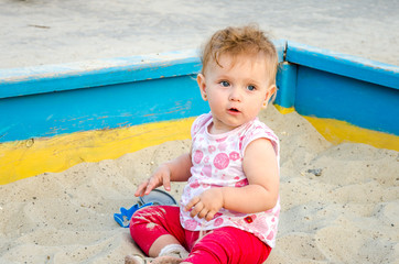 Little beautiful girl baby play in the sandbox and sand toys on the playground