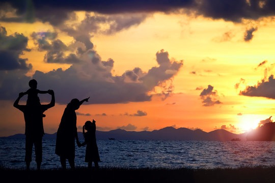 A silhouette of a happy family, mother, father,girl,son and infant (women pregnancy)  on sunsetbach  (copy space or text on right area)