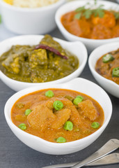 Aloo Matar - Potatoes and green peas cooked in a mild creamy tomato gravy. Chapattis and other vegetarian curries on background.
