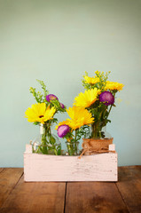 summer bouquet of flowers on the wooden table with mint background