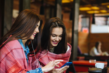 Two girl sitting listening to music with a smartphone