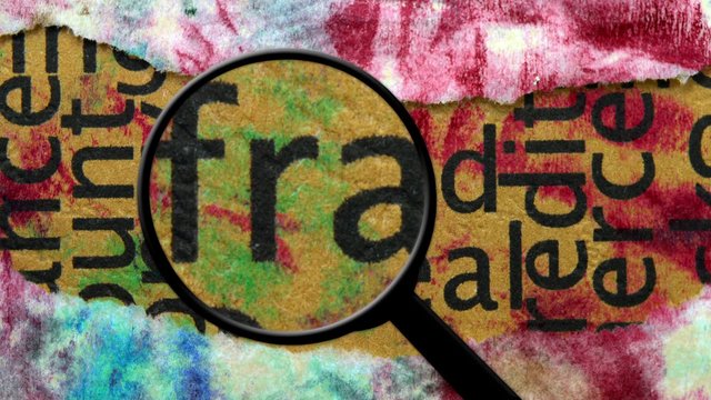 magnifying glass on fraud text 
