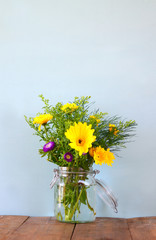 summer bouquet of flowers on the wooden table with mint background