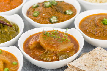Vegetarian Curries - Selection of South Asian vegetarian curries in white bowls. Paneer Makhani, Palak Paneer, Aloo Matar, Baigan Bharta, Chilli Potatoes and Bhindi Masala, Pilau Rice and Chapattis.

