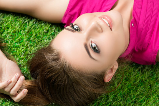Young beautiful girl laying on the grass in park