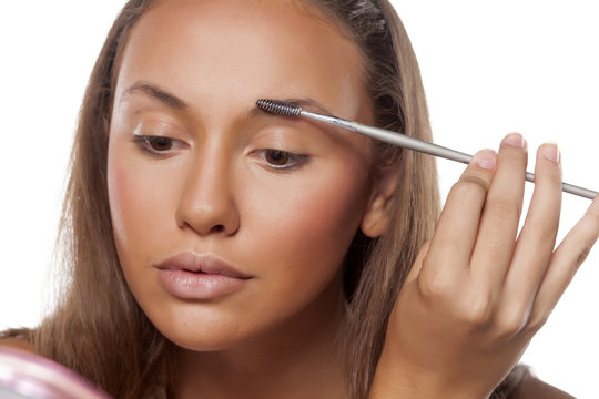 girl comb her eyebrows with a brow brush