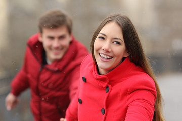 Happy couple running towards camera in winter
