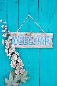 Welcome sign with flowers hanging on rustic door