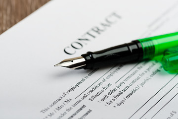 Pen and contract papers on wooden desk