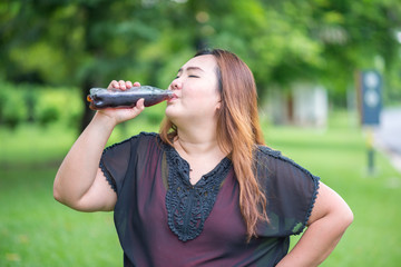Fat woman drink cola in garden