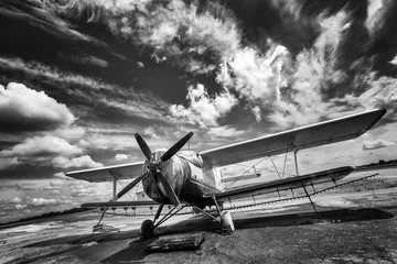 Fotobehang Oud vliegtuig Oud vliegtuig op veld in zwart-wit