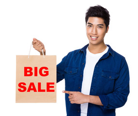 Man finger point to shopping bag for showing phrase of big sale