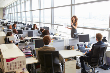 Female manager addressing workers in open plan office