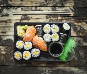 Sushi menu set  in black transport box on dark wooden background, top view