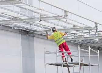 Worker painting awning on scaffolding