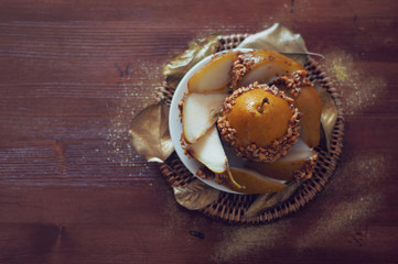 Caramelized pear dipped with peanuts decorated with golden leave