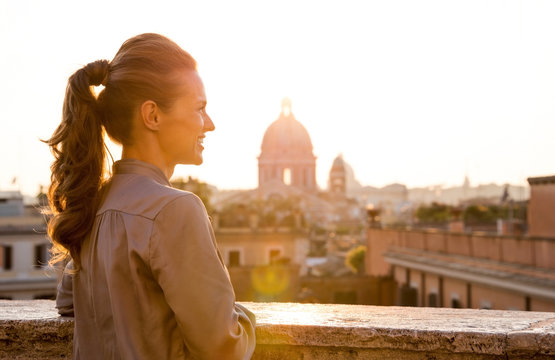 Elegant woman looking out at sunset over the city of Rome