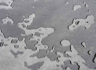 Water droplets, irregular shapes and sizes, on grey stone surface. Texture.