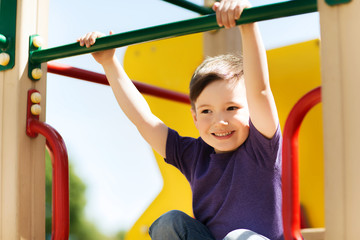 Fototapeta premium happy little boy climbing on children playground