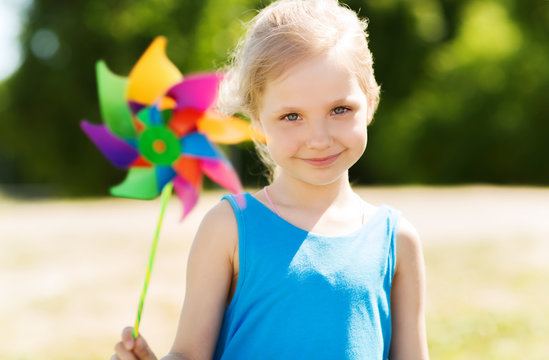 happy little girl with colorful pinwheel at summer
