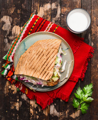 doner kebab with meat cutlets and vegetables on a plate with a red napkin and garlic sauce On wooden rustic background, top view