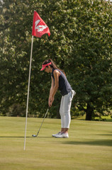 Obraz premium Portrait of a young woman swinging her club on a golf course.