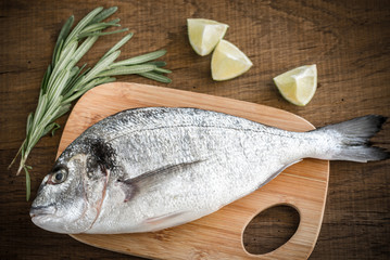 Fresh dorada with ingredients on the wooden board