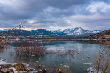 Frozen lake in winter with snowy mountains at background
