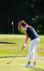 A young woman swinging her club on a golf course