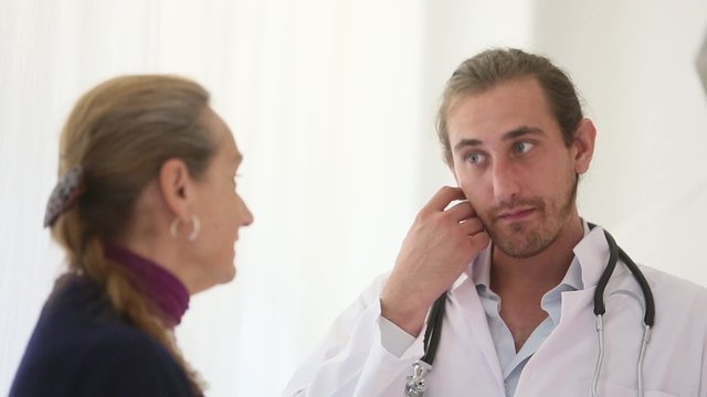 A male and young doctor speaking seriously with a female patient nodding