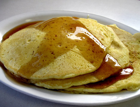 A stack of pancakes slathered with butter and syrup.