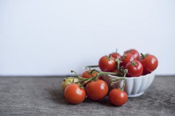 Bowl of tomatoes on the vine in a white bowl with white background