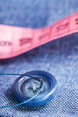 attaching of button to blue material by needle
