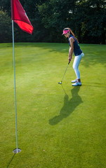Sporty woman playing golf on a green field during a sunny day