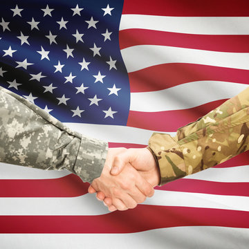 Men in uniform shaking hands with flag on background - United States