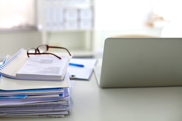 Stack of papers and glasses lying on table desaturated