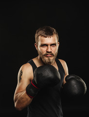 Athletic bearded boxer with gloves on a dark background