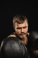 Athletic bearded boxer with gloves on a dark background