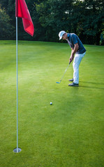 Obraz premium a man with a cap playing golf on a green field