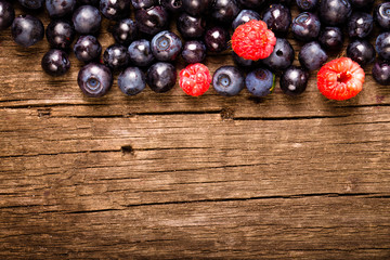 Forest blueberries and raspberries on an old wooden board