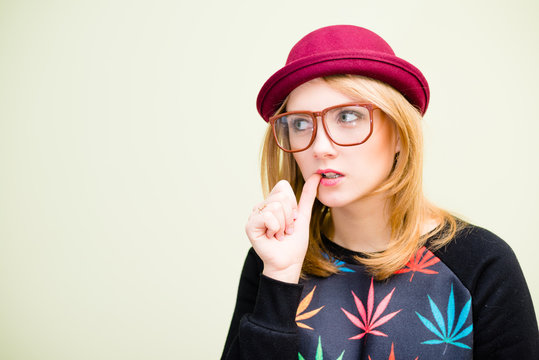 Sad funny hipster in glasses and hat biting thumb 