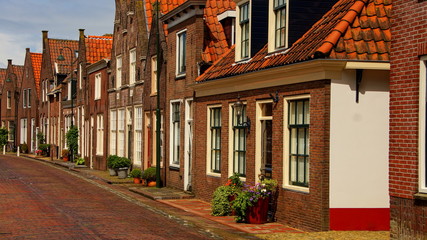 sonnige Häuserfronten  in Monnickendam nach Regen mit dunklem Himmel