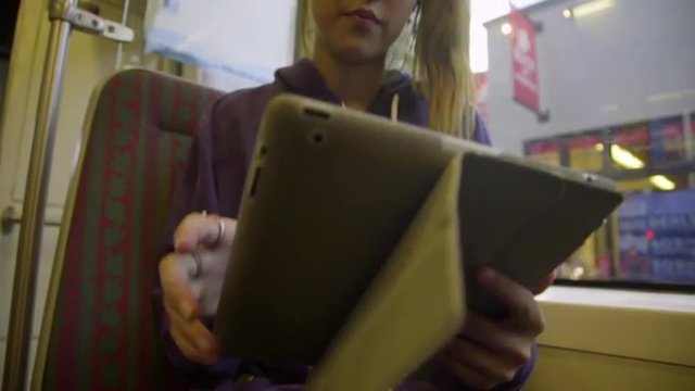 Attractive asian teen uses tablet computer on the subway